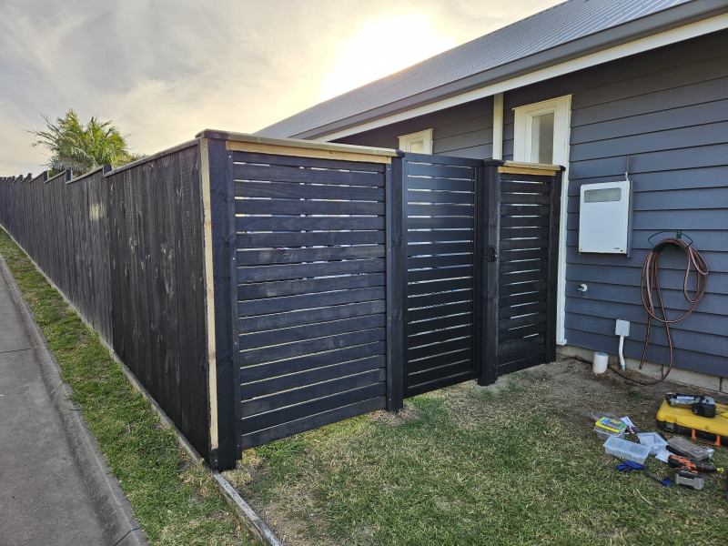 Horizontal black slat fence and gate at a residential property