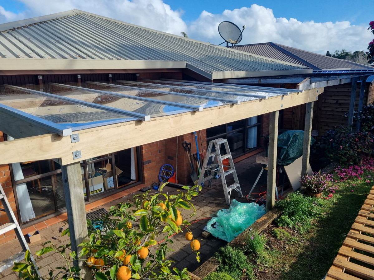 Timber pergola with a polycarbonate roof over a paved outdoor area
